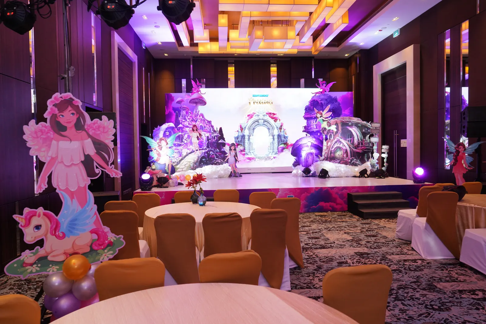 Fairy garden themed ballroom with a large LED backdrop, fairy cut-outs, toadstool houses and banquet seating